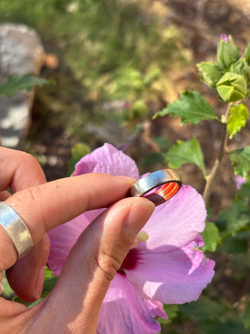 Make Your Own Wedding Band custom skateboard wood and metal ring held near a pink flower