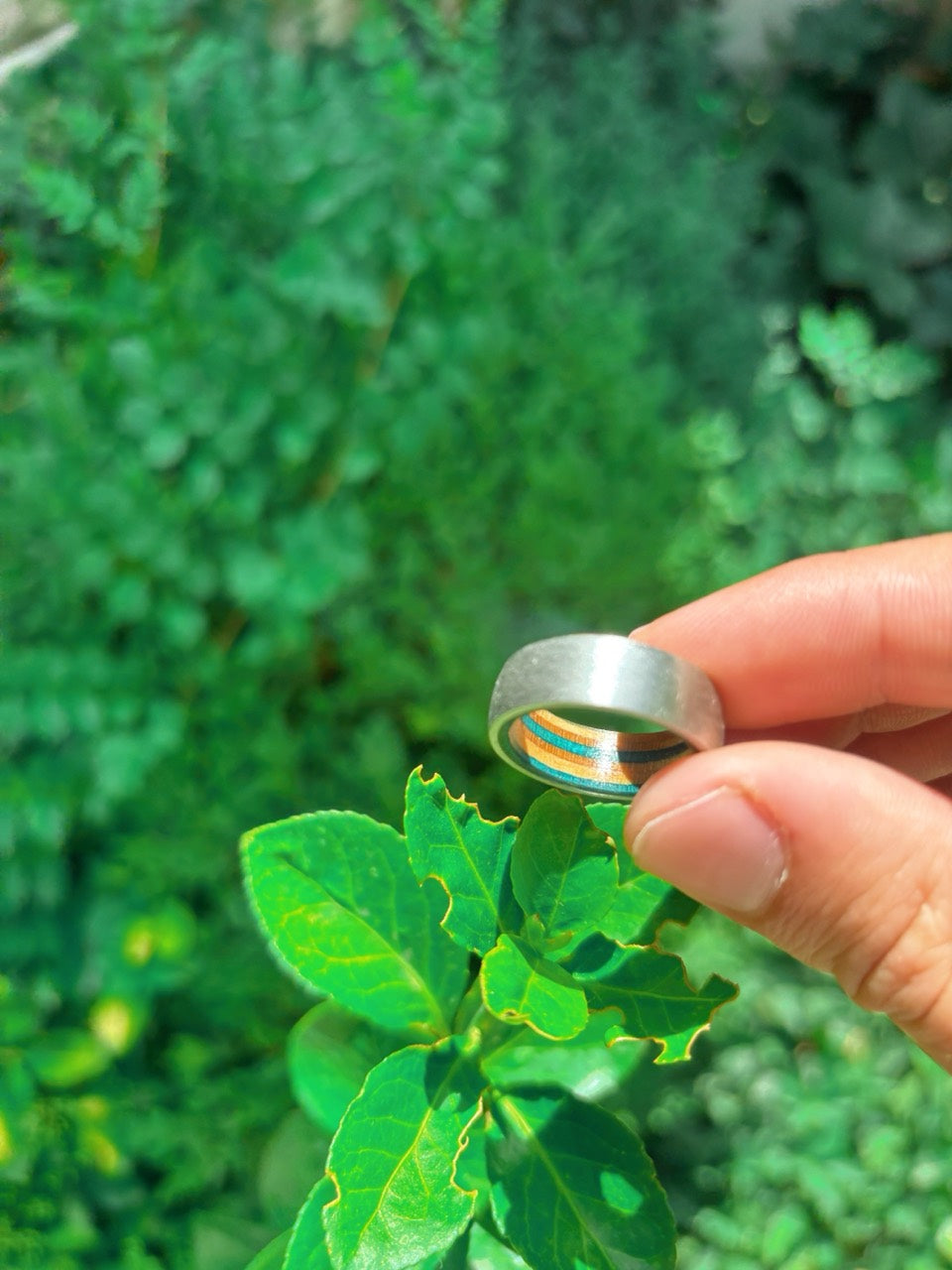 Make Your Own Wedding Band custom skateboard wood and metal ring held near green leaves