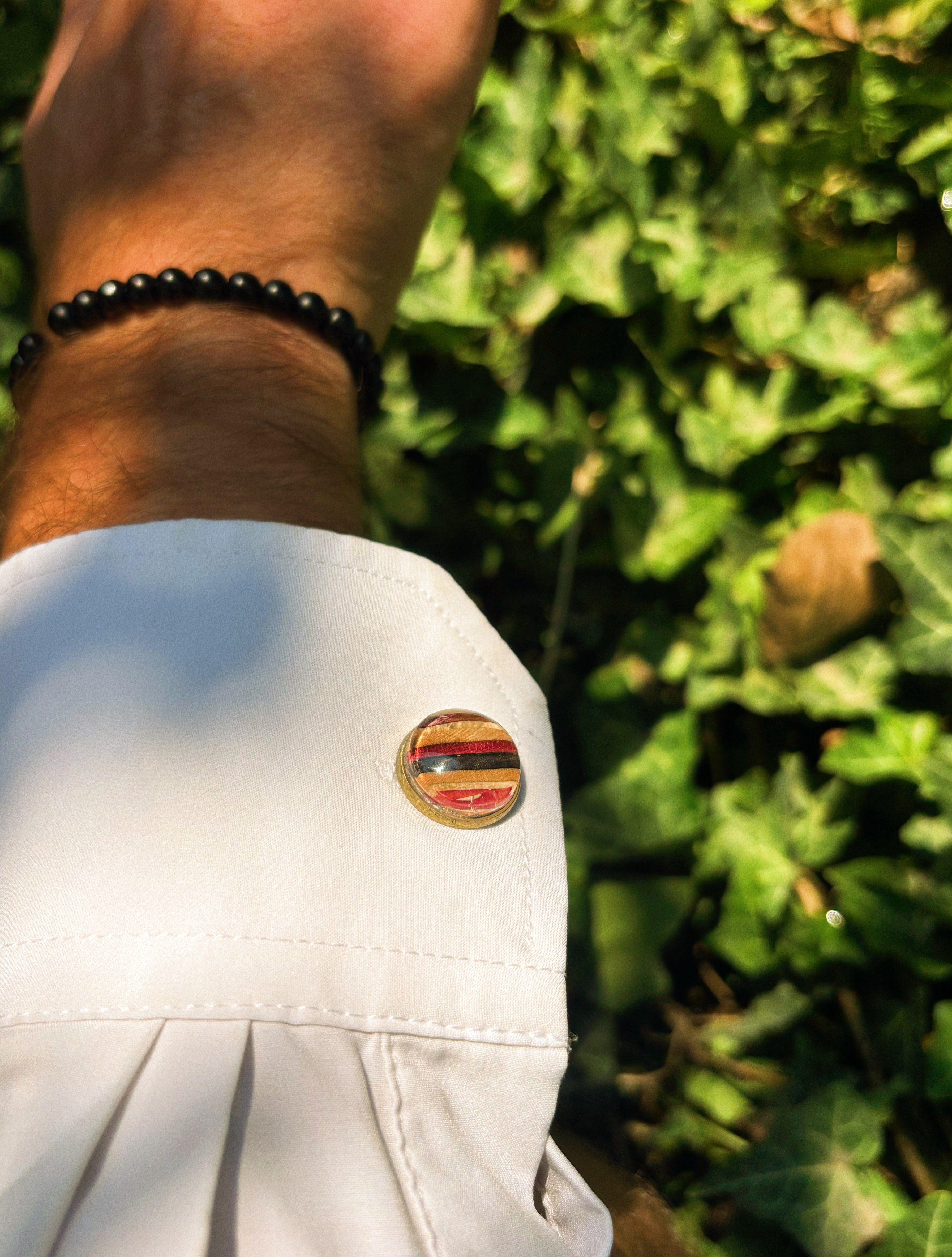 Deep Rose recycled skateboard cufflink with red and pink layers on a white shirt cuff