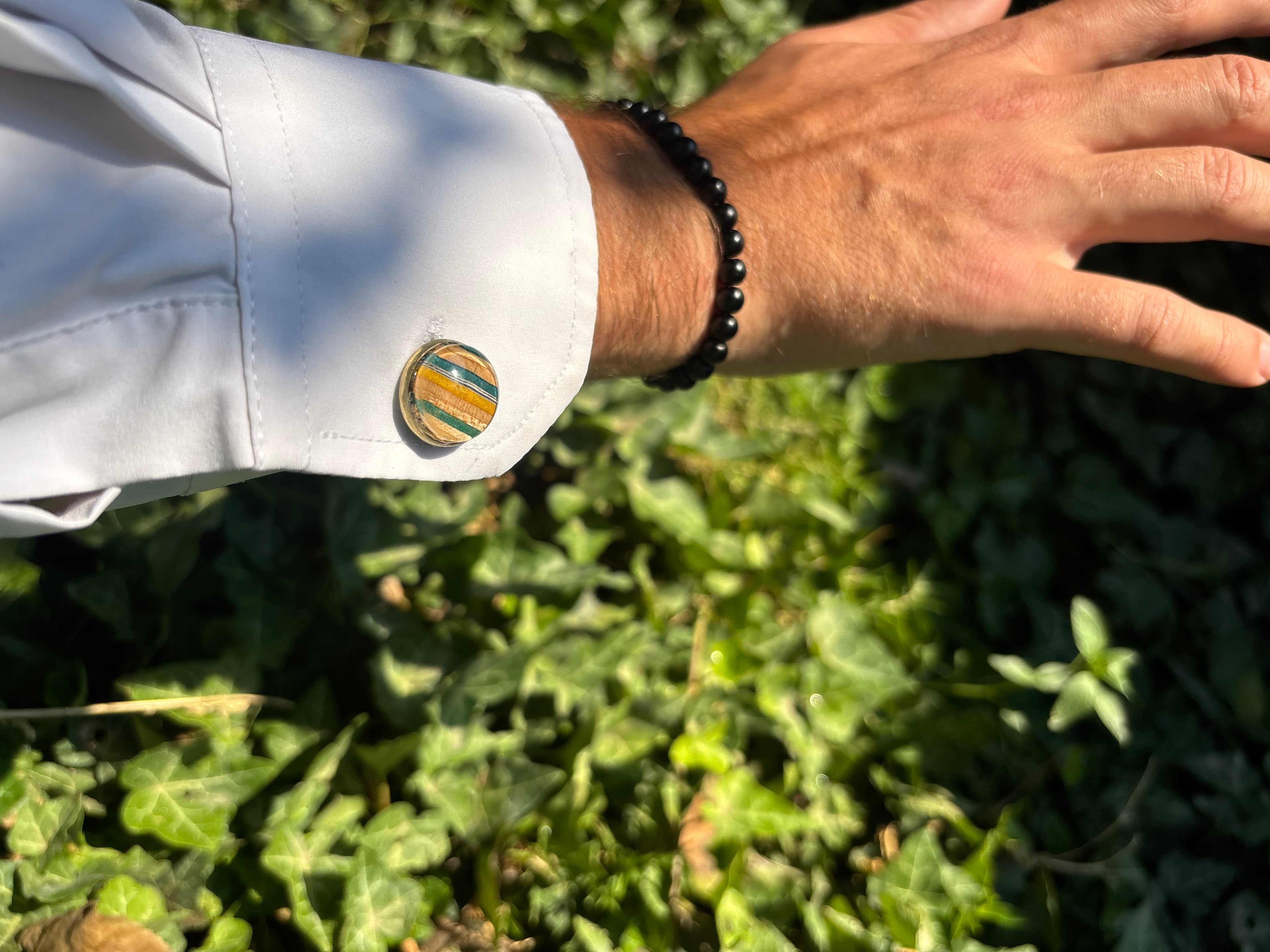 Summer Breeze recycled skateboard cufflink with green and yellow layers on a white shirt cuff
